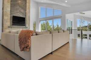 Vacation rental living room with large sectional sofa and windows showcasing the aspen trees outside the big windows.