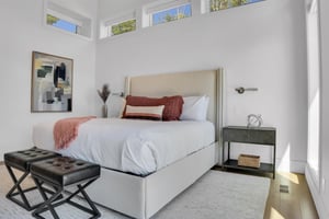 Vacation rental main suite with wood end night stands and leather stools at the end of the bed.