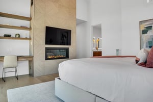Vacation rental main stuite with stone fireplace and built in floating shelves and desk area next to it.