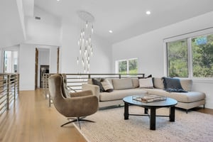 Vacation rental second living room with white walls, recessed lighting, striking chandelier, and neutral toned furniture.