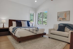 Vacation rental bedroom with a king size bed, wooden bedframe, crisp linens and blue accent pillows and throw.