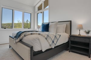 Vacation rental bedroom with a king size bed and upholstered and wood bed frame with crisp white linens and blue accent pillows.