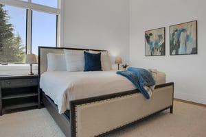 Vacation rental bedroom with a king size bed, solid wood end tables and modern art.