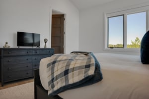 Vacation rental bedroom with solid wood dresser and flat screen TV.