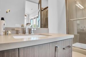 Vacation rental en sutie bathroom with light wood cabinets and modern fixtures.