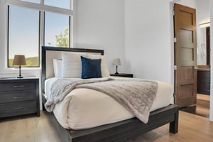 Vacation rental bedroom with a queen size bed and tall windows and solid wood furniture.