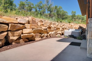 Vacation rental backyard surrounded by a rock wall, oak grove, and private hot tub.