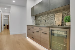 Vacation rental wet bar with beverage cooler, tiled backsplash, and sink.