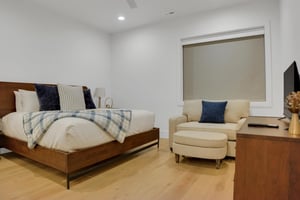Vacation rental bedroom with kind size bed and comfortable seating in light cream with blue accent pillows.