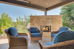 Vacation rental covered patio with large stone fireplace and comfortable seating for 4 guests.