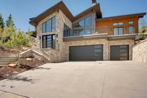 Exterior of the vacation rental feature the high peaked roof lines, stone and wooden facade, and large deck.