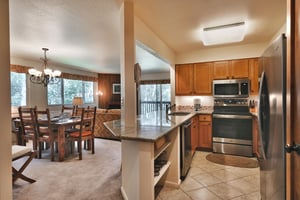Fully equipped kitchen with granite countertops and tiled floors, wooden cabinets and stainless steel appliances