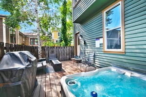 Secluded private back patio with bubbling hot tub, gas grill, and patio furniture set with gas firepit