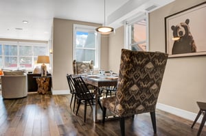 Dining area with a wood table, four wooden chairs, and two upholstered chairs at the ends, with views into the living room.