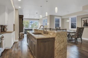 Open concept kitchen with sink in the island, overlooking the open concept living area and dining area.
