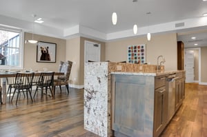 A granite waterfall island in the kitchen with a view of the open floor plan dining area.