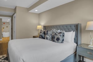 A grey upholstered kingsize bed with stylish furnishings and serenecolored walls.