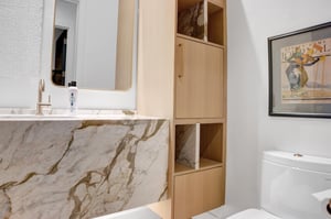 Half bathroom on the main level with a beautiful quartz sink basin, large mirror, and lightcolored wood builtin cabinets.