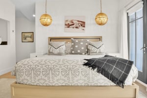 The main suite king bed has two globe pendant lights hanging on each side and a sepia toned picture above the headboard.