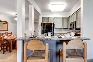 The Snow Flower 12s kitchen breakfast bar has 2 wooden stools and the bar is set with dishes, placemats, etc for 2.