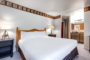 Snow Flowers main suite has a king size bed with white linens, 2 end tables and lamps and attached bathroom.