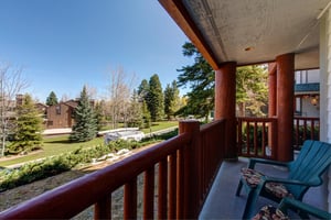 Snow Flower 12s deck with wooden railing, chairs, overlooking many trees and blue sky.