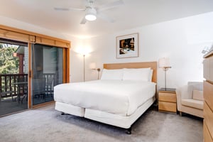 Snow Flower 29s main suite king size bed with wooden headboard and large sliding glass doors leading to a covered patio.