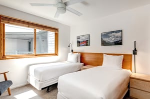 Two twin beds with crisp white linens, shared night stand in the middle and two pictures above the beds.