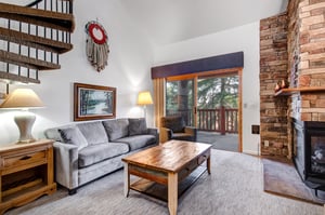 Snow Flower 31s living room with grey upholstered couch, nature picture and dream catcher on wall, and sliding glass doors.