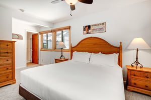 Snow Flower 31s loft with a king size bed with crisp white linens, night stands with lamps, 2 windows, and picture on wall.