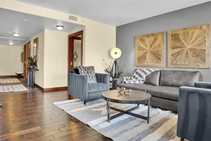 Lowell 304s living room has grey couch, loveseat, and chair, and interesting modern floor lamp.