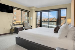 Lowell 304s main suite with king size bed, large picture windows, and chair with floor lamp.