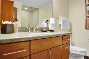 One sink vanity with warm wood cabinets, light color countertop, large mirror and Park City Lodging toiletries.