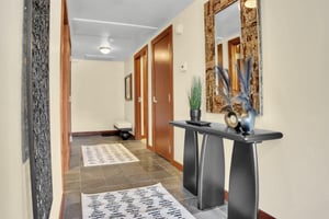 Lowell 304s entryway with stylish table, vases, mirror, and a hallway beyond.