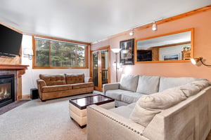 Snow Flower 43s living room has a grey sectional sofa, brown leather couch, white coffee table, and large mirror on wall.