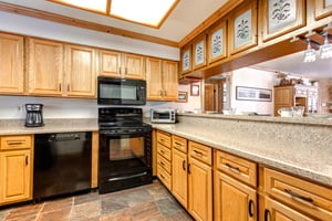 Snow Flower 43s kitchen with black appliances, oak cabinets, breakfast bar with short ceiling mounted cabinets above.
