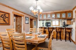 Snow Flower 43s dining room is situated next to a breakfast bar with 4 wooden stools and place settings for 4 guests.