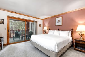 Snow Flower 43s suite has a kingsize bed, a mauve wall and artwork above a wood headboard, and sliding glass doors.