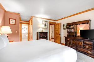 Snow Flowers 43s main suite has a kingsize bed, with white linens, dark wood furniture and light wood trim around the room.