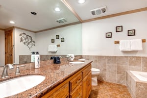 Snow Flower 43s en suite bathroom has a medium toned wood double sink vanity, two sinks, large mirror and white toilet.