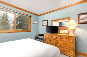 Snow Flower 43s second bedroom has a queensized bed, wooden dresser, and a TV, lamp, and mirror on the dresser.