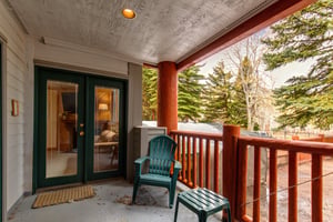 Snow Flower 43s deck with wooden railing, green chair and table, and green glass doors leading to the inside.
