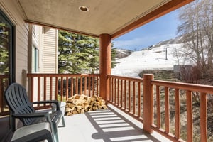 Snow Flower 65s view from the patio of Park City Mountains snowcovered terrain park, lift, and the wood deck railing.
