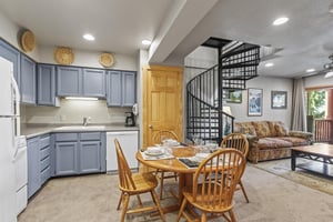 Snow Flower 72s kitchen with blue cabinets and white appliances and open to living room and a black spiral stair case.