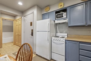 Snow Flower 72s kitchen with blue cabinets and white appliances.