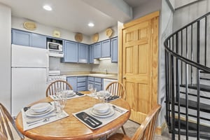 Snow Flower 72s kitchen with blue cabinets, white appliances, and dining table set for four guests.