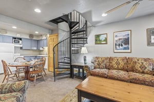 Snow Flower 72s kitchen with blue cabinets and white appliances and open to living room and a black spiral stair case.