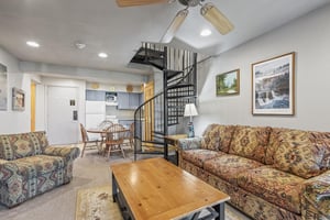 Snow Flower 72s kitchen with blue cabinets and white appliances and open to living room and a black spiral stair case.