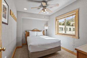 Snow Flower 72s bedroom with a queen bed, white sheets and pillows, greige walls and blonde wood accents.