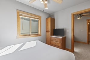 Snow Flower 72s bedroom with queen bed, wooden dresser, and ceiling fan.
